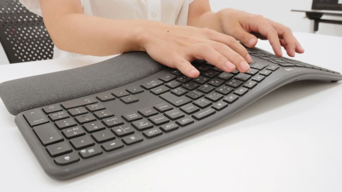 Woman using ergonomic keyboard on white desk