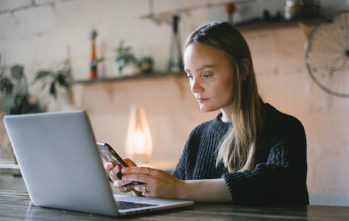 Woman using laptop and smartphone at desk