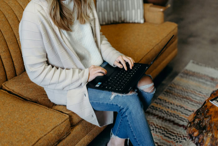 Woman using laptop while sitting on yellow sofa