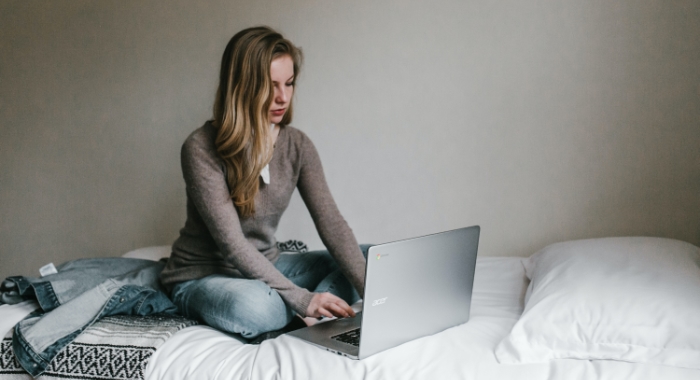 woman using laptop on bed