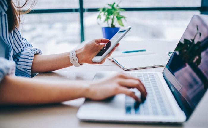 Woman using phone and laptop