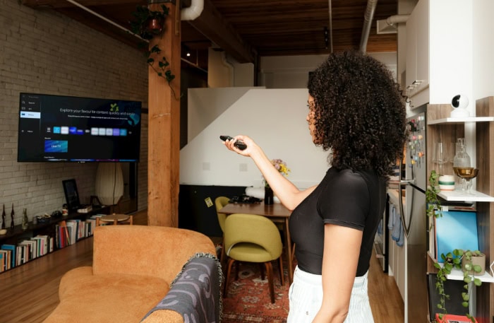 Woman using remote to control smart TV in living room