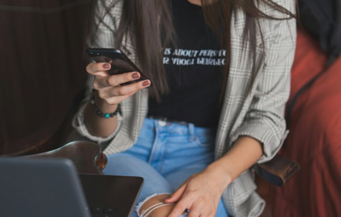 Woman using smartphone and laptop while wearing casual clothes