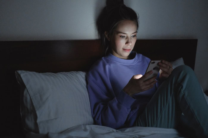 Woman using smartphone in bed at night