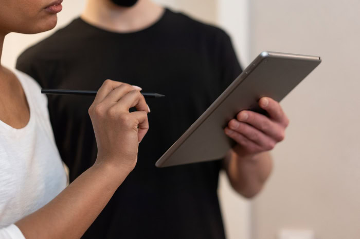Woman using stylus on tablet held by colleague