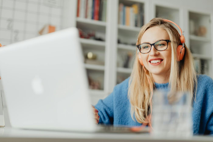 Woman wearing headphones using a laptop at home