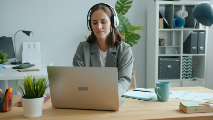 Woman with headphones working on laptop at desk
