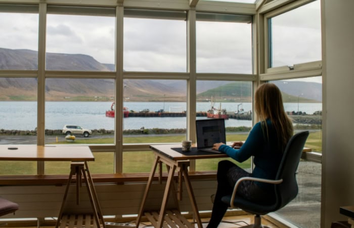 Woman working on a laptop with a scenic ocean view