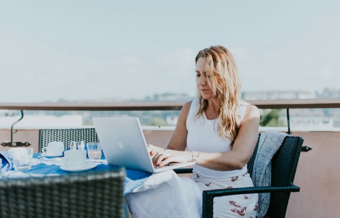 Woman working on laptop at outdoor table with cityscape