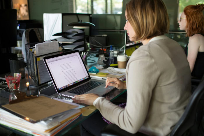 Woman working on laptop computer at office desk resized