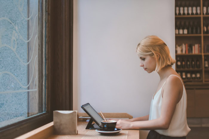 Woman working on tablet at coffee shop counter