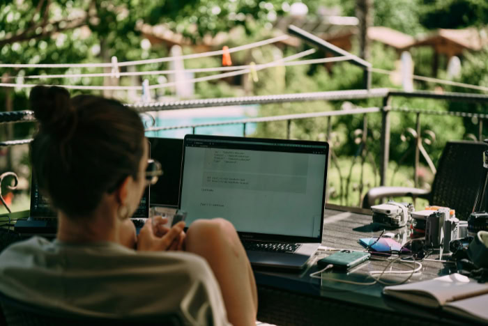 Woman working remotely on laptop at outdoor desk