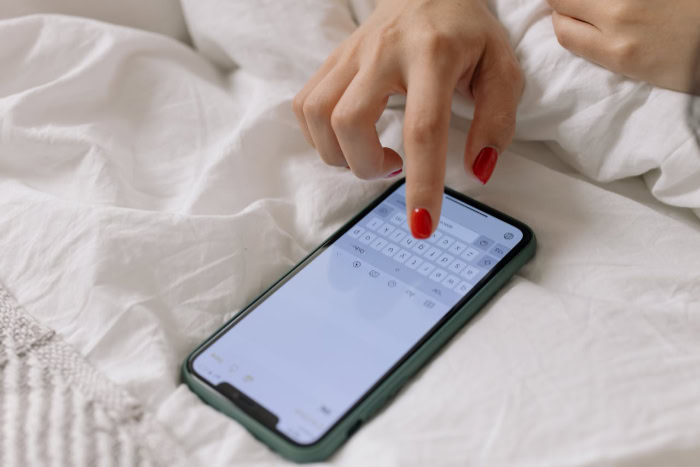 Womans hand with red nails typing on smartphone