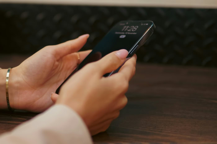 Womans hands holding a smartphone at a table