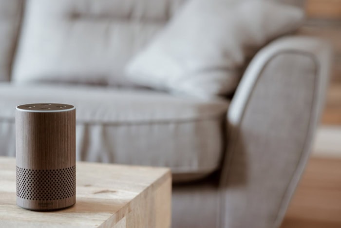 Wooden Amazon Echo smart speaker beside gray couch