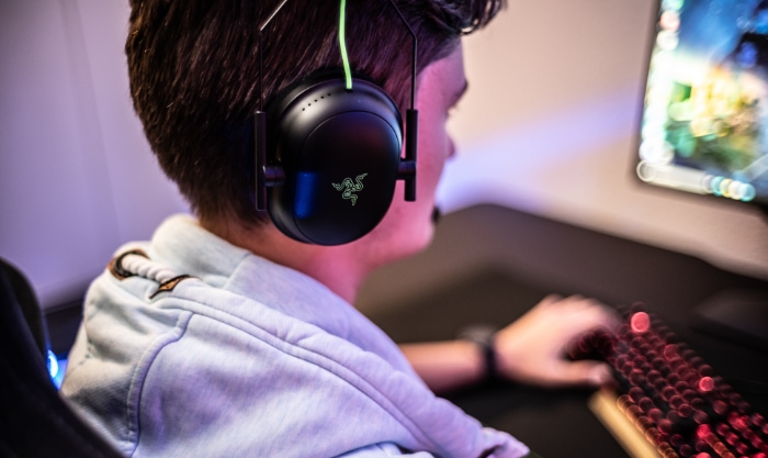 Young person gaming with over ear headphones at a computer desk