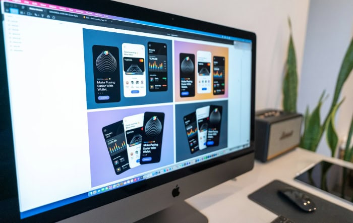 iMac displaying mobile app design mockups on desk with plant