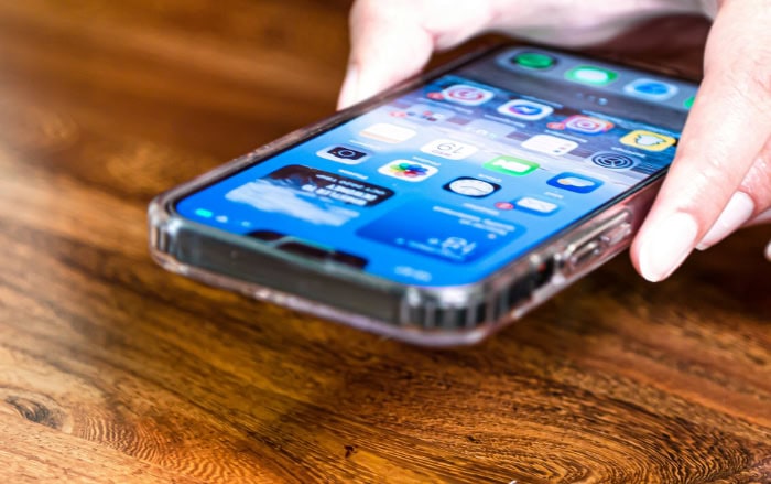 iPhone screen showing app icons on wooden surface