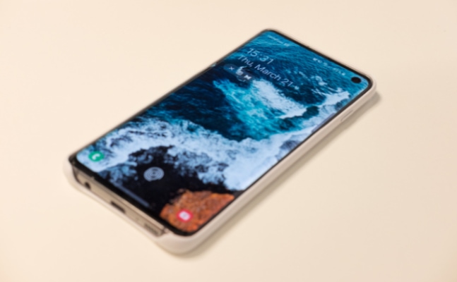 Smartphone displaying ocean wallpaper on cream surface